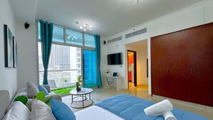 A hotel room with a bed, a desk, a TV, and a view of the city. - Luxury Brand New Studio  (Dubai)