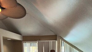 Quarto com cama, penteadeira, escrivaninha e janela com persianas.