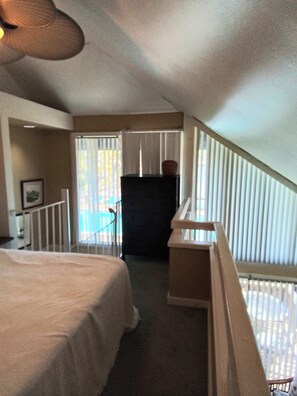 A bedroom with a bed, a dresser, a desk, and a window with blinds.