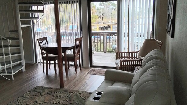 Uma sala de estar ampla com um sofá grande, um espaço de jantar com cadeiras e uma escada.