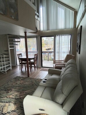 A spacious living room with a large sofa, a dining area with chairs, and a staircase.