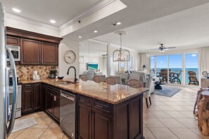 A spacious kitchen with dark wooden cabinets, a granite countertop, and a large island. - Beach Front w/Wrap Around Balcony Free Pickleball Tides Unit 1101 (Miramar Beach)