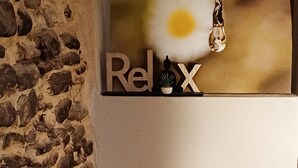 A wall with a stone texture on the left and a sign with the word "Relax" and a keychain with a key and a plant. - Romantic Suite con Jacuzzi (Isolabona)