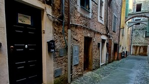 A narrow cobblestone street flanked by historic buildings with stone walls and wooden shutters. - Romantic Suite con Jacuzzi (Isolabona)