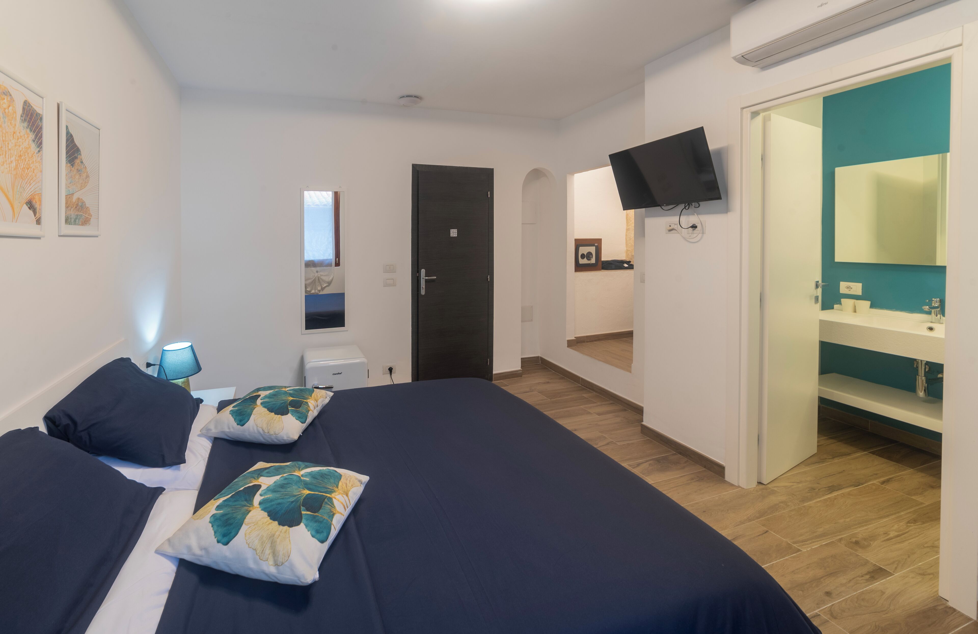 Een slaapkamer met twee bedden, een televisie, een badkamer met spiegel en kunstwerken aan de muren.
