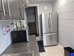 A modern kitchen with stainless steel appliances, a built-in microwave, and a first aid kit on the wall. - Spacious 1-bedroom basement unit (full bathroom/shared laundry) (Gatineau)