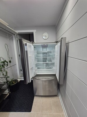 A modern kitchen with a built-in refrigerator, a clock on the wall, and a potted plant. - Spacious 1-bedroom basement unit (full bathroom/shared laundry) (Gatineau)