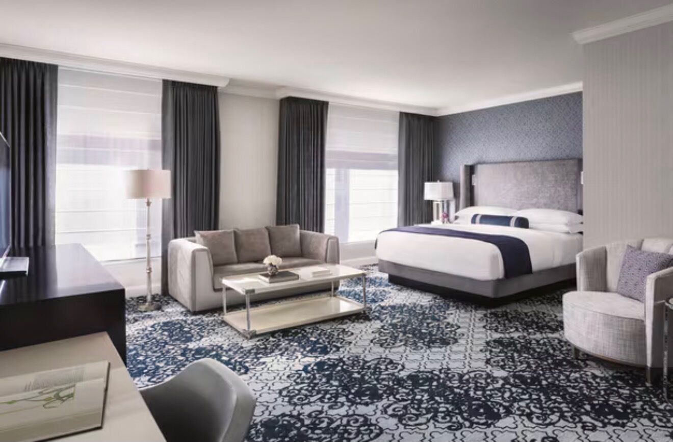 Una habitación de hotel con una cama, un sofá, una mesa de centro y una silla.