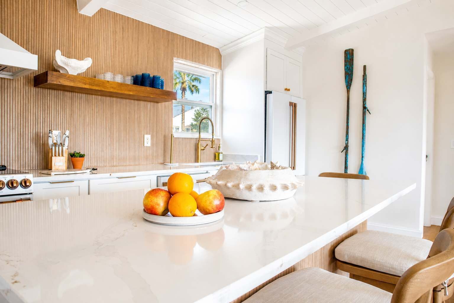 A modern kitchen with a marble countertop, a fruit bowl, and a wooden island.