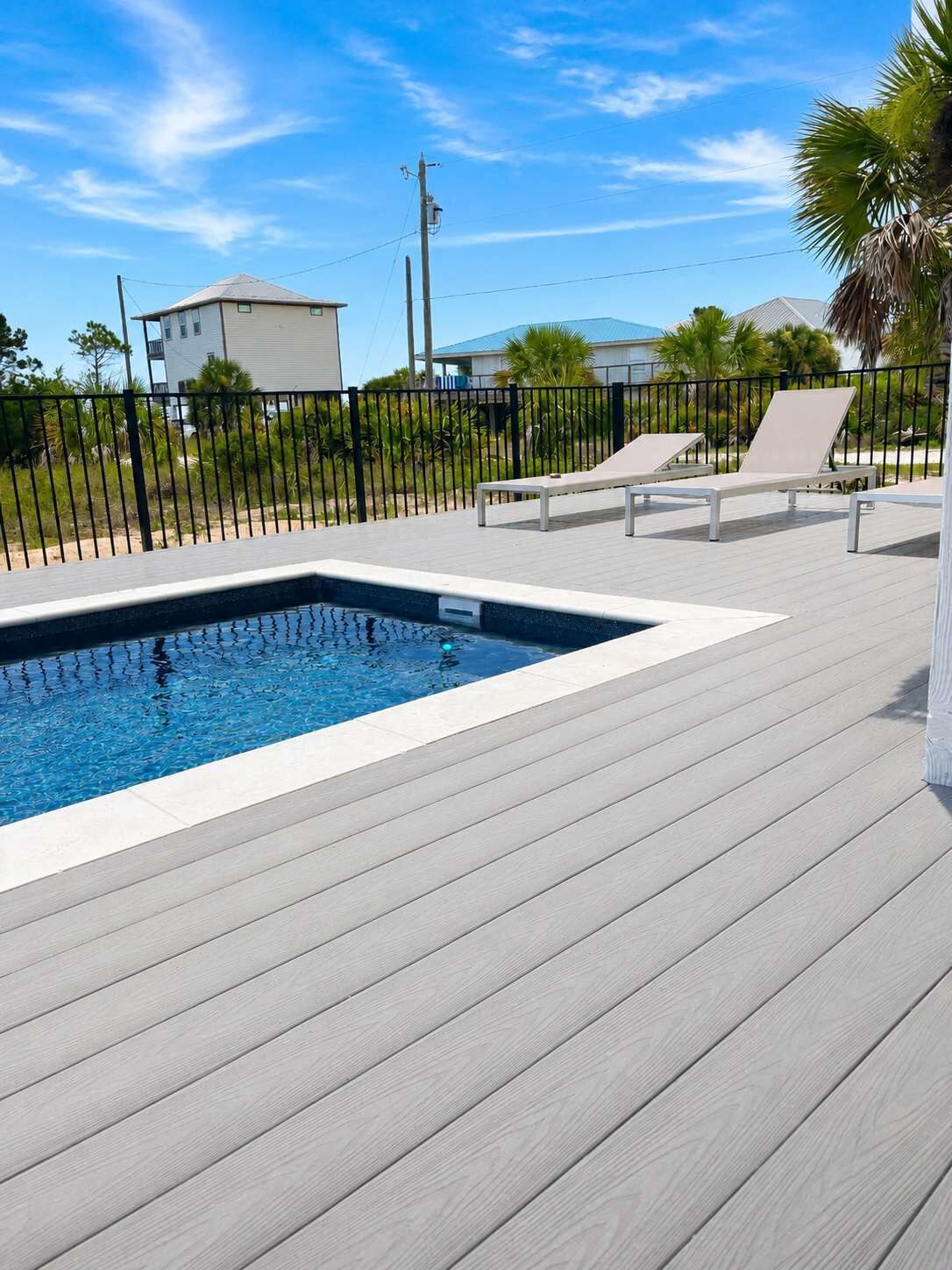 Una piscina con sillas de descanso y una terraza de madera.