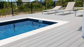 Una piscina con sillas de descanso y una terraza de madera.