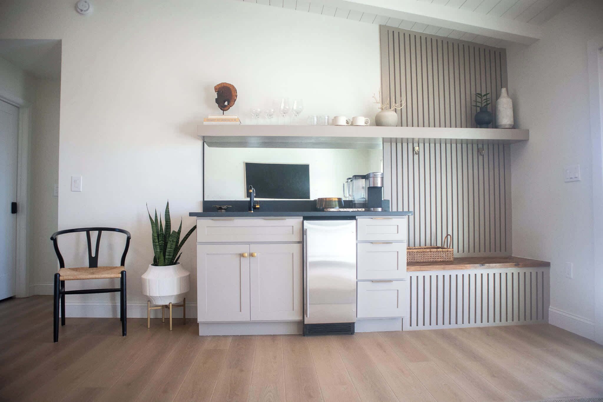 Cocina compacta con armarios blancos, encimera negra y un banco empotrado.