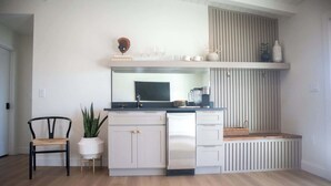 Une cuisine compacte avec des meubles blancs, un plan de travail noir et un banc intégré.