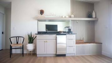 Cocina compacta con armarios blancos, encimera negra y un banco empotrado.