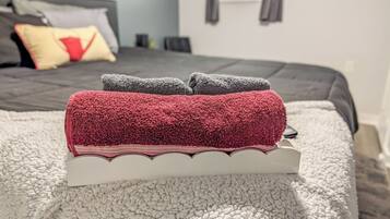 Un asciugamano piegato in rosso e grigio su un vassoio bianco in una camera d'albergo.