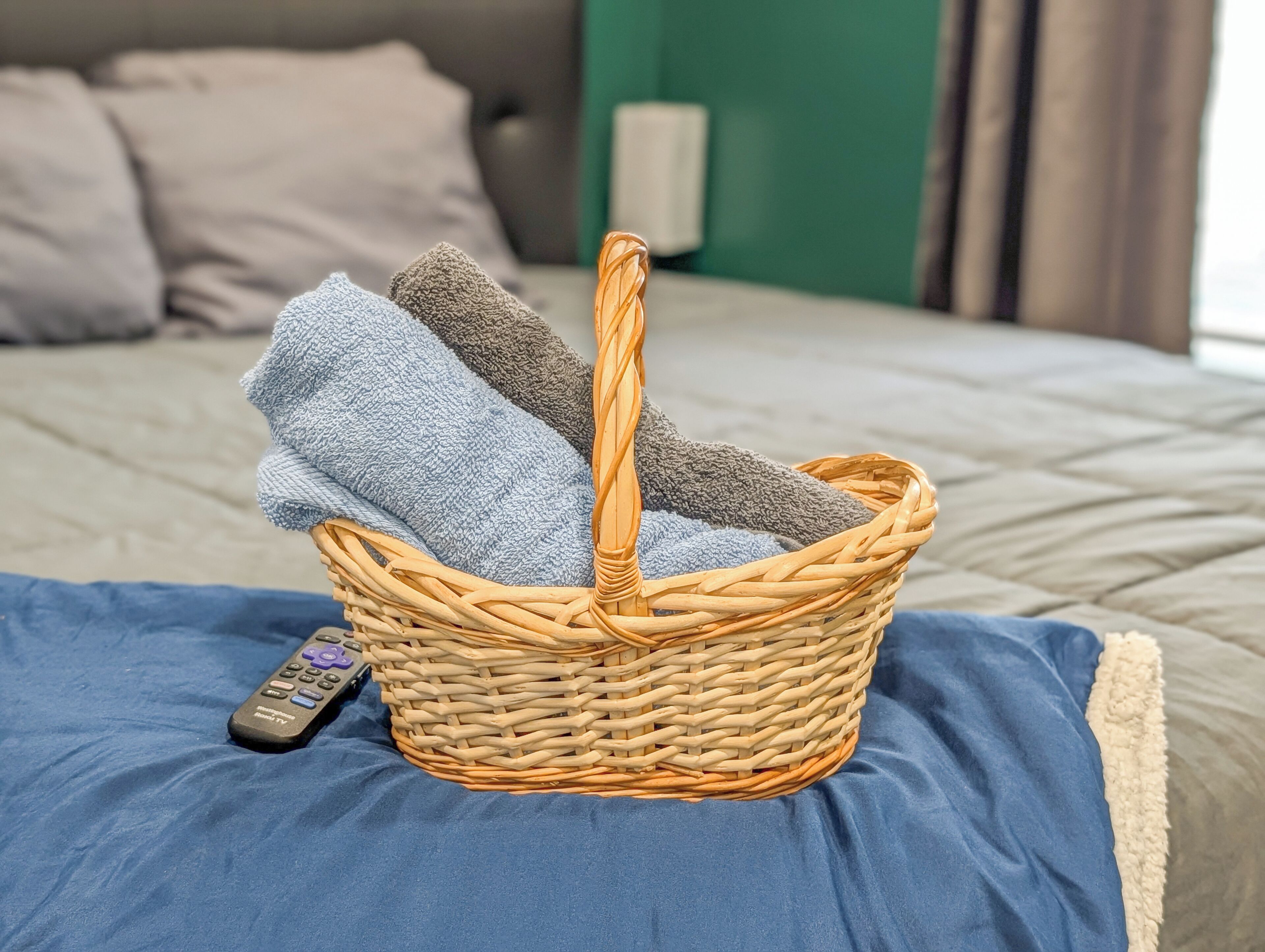 Ein Korbwäschekorb mit Handtüchern auf einem Bett.