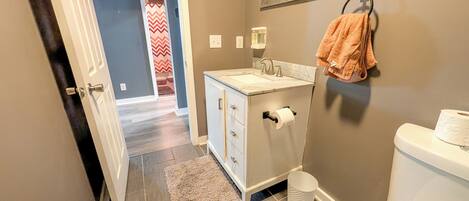 A bathroom with a white sink, a mirror, a towel rack, and a toilet.