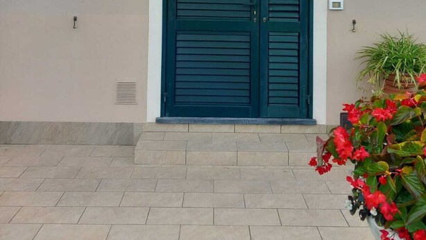 A building with a double door, a small window, and a potted plant with red flowers. - At the Gates of Pisa; apartment with garden, pets allowed (Madonna Dell'acqua)