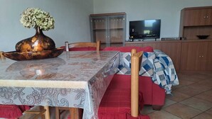 A dining area with a table covered in a patterned tablecloth, wooden chairs, and a vase with flowers. - At the Gates of Pisa; apartment with garden, pets allowed (Madonna Dell'acqua)
