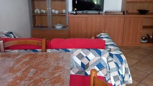 A room with a bed, a TV, a wooden cabinet with glass doors, and a tiled floor. - At the Gates of Pisa; apartment with garden, pets allowed (Madonna Dell'acqua)