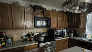 A kitchen with wooden cabinets, a microwave, an oven, and a sink. - Spacious 4-bedroom house with AC in fantastic Houston neighborhood (Houston)