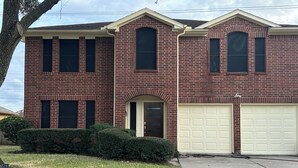 A two-story brick house with a front garage, a central entrance, and a small front yard with a hedge. - Spacious 4-bedroom house with AC in fantastic Houston neighborhood (Houston)