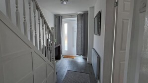 Un passadís amb una escala, una porta al final i un radiador a la paret.