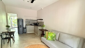 A modern living room with a sofa, a dining table with chairs, a kitchen area, and a ceiling fan. - Loft Private (Cartagena)