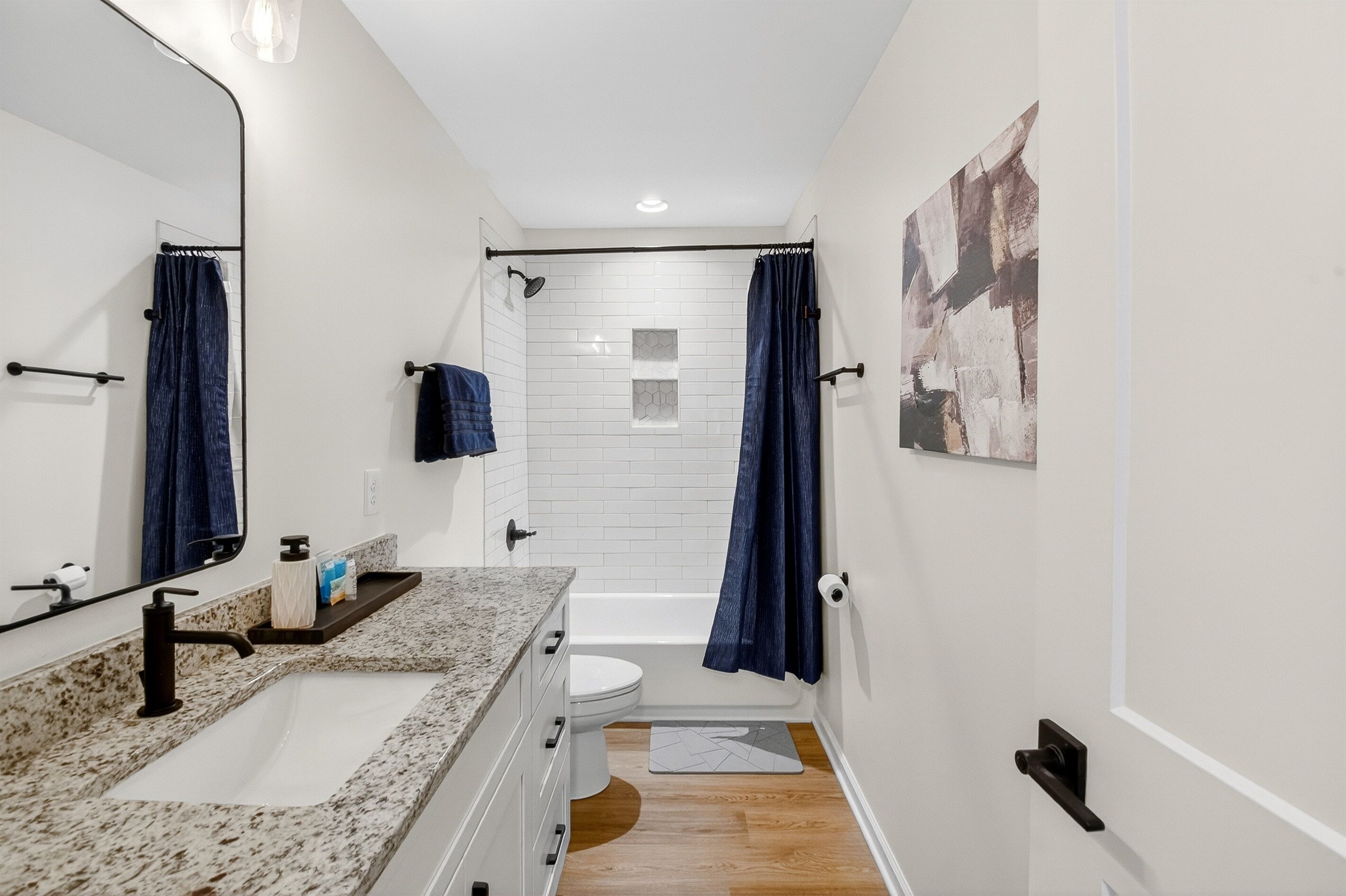 Un baño moderno con un lavamanos blanco, una cortina de ducha azul oscuro y un inodoro blanco.