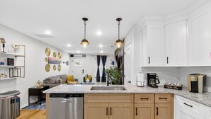 A modern kitchen with white cabinets, a granite countertop, and stainless steel appliances. There is a coffee bar area with a coffee machine and a coffee mug set. - MusicCityRetreat|3BR2BA|Arcade|Sleep8|EasyDTCommute (Madison)