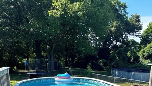 Une piscine avec une terrasse en bois et un jouet flottant.