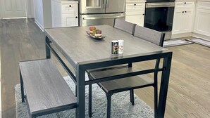 Eine moderne Küche mit weißen Schränken, Edelstahlgeräten und einem Holzespeisetisch mit Bänken.