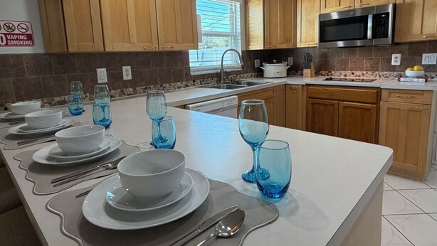 A kitchen with wooden cabinets, a microwave, and a sink.