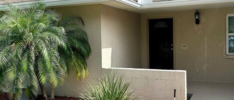 A single-story house with a beige exterior, a dark front door, and a small porch area.