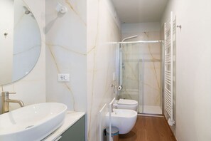 Ein Badezimmer mit einem großen, ovalen Waschbecken, einer Toilette und einer Duschkabine.