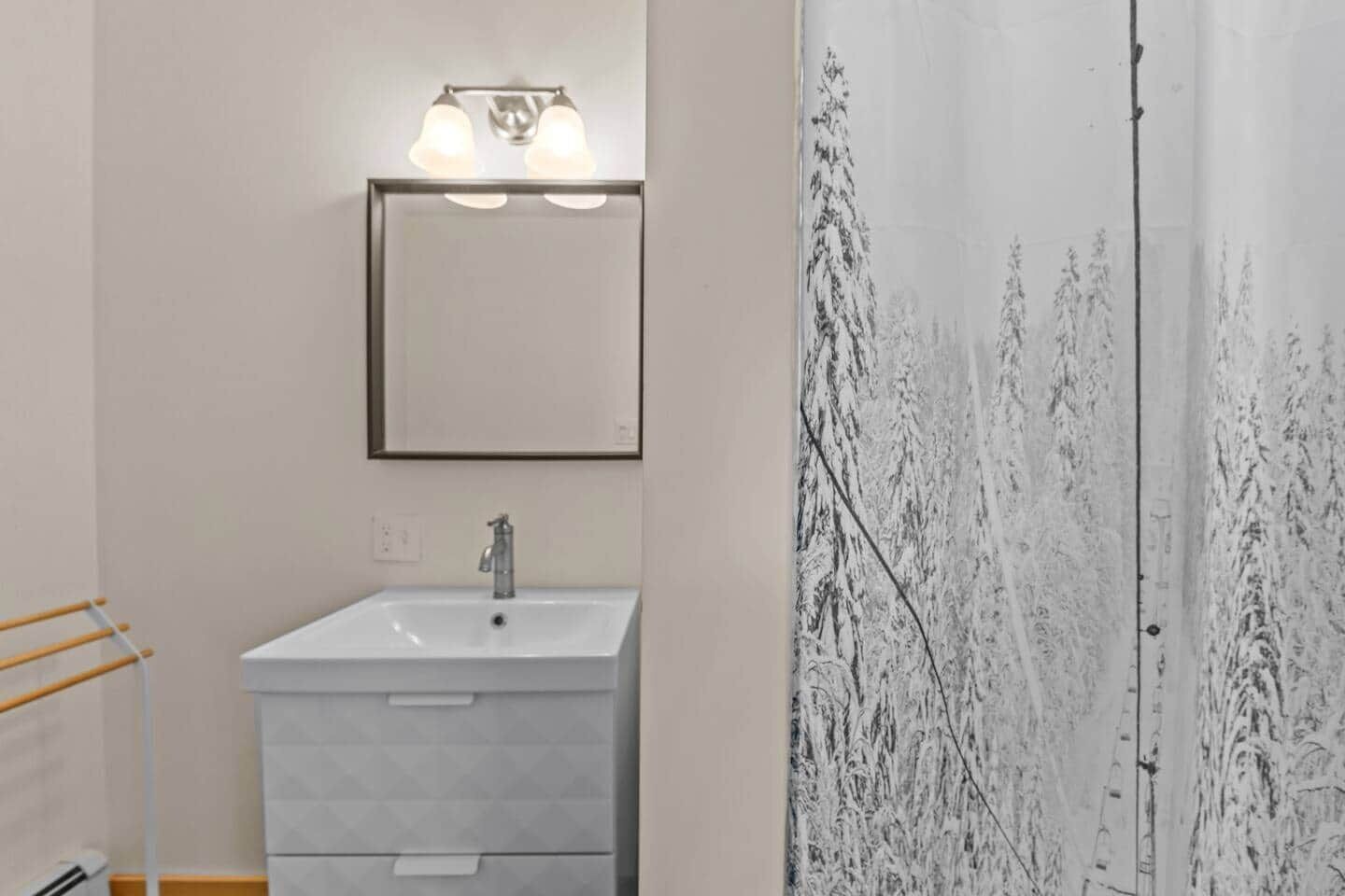 A bathroom with a white sink, a mirror, and a towel rack.