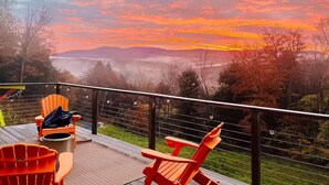 Une terrasse avec coin salon extérieur, offrant une vue sur un paysage arboré et, au loin, sur des montagnes.