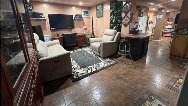A living room with a sofa, a coffee table, a TV, and a bar area.