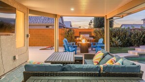 Eine Terrasse im Freien mit Grill, blauen Stühlen und einer gepolsterten Sitzecke.