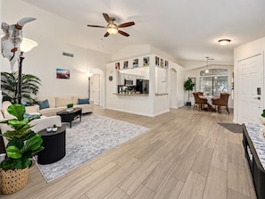 A spacious living room with a sofa, coffee table, and a dining area with chairs and a table. - Private Pool Oasis Near Spring Training & Luke AFB (Surprise)
