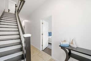 Eine Treppe führt zu einem Schlafzimmer mit einem Bett, einem Nachttisch und einem kleinen Tisch mit Gegenständen darauf.