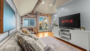En moderne stue med et stort fladskærms-tv, en sofa og en loftventilator.