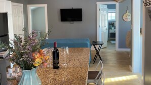 Une cuisine avec un plan de travail en granit, un vase rempli de fleurs, une bouteille de vin et un téléviseur fixé au mur.