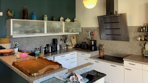 Cozinha moderna com bancadas de granito, armários brancos e um suporte para panelas suspenso.