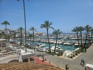 Un port esportiu amb barques, palmeres i edificis al fons.