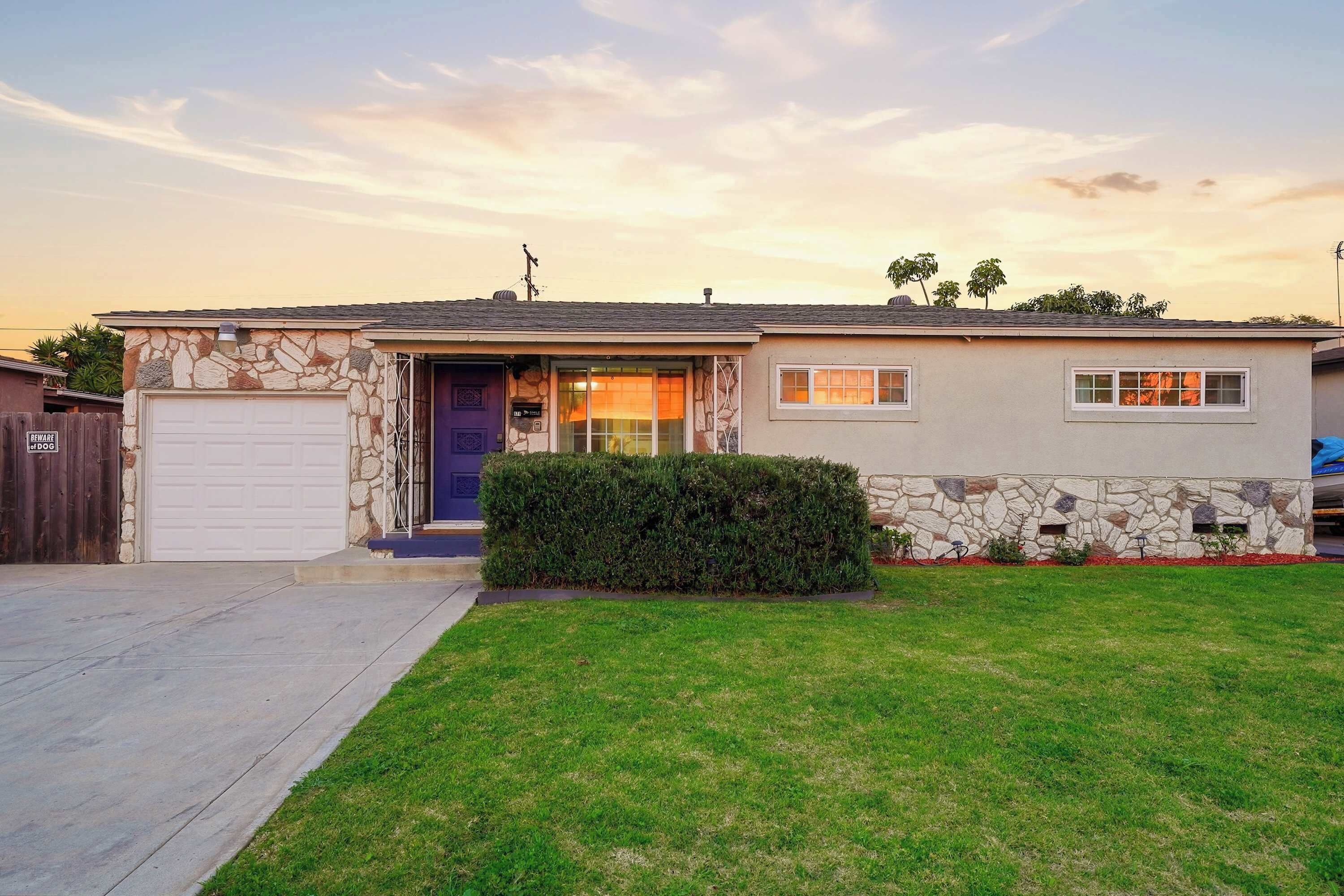 A single-story house with a stone facade, a garage, and a well-maintained lawn.
