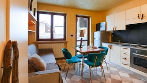 Una cocina compacta con comedor, un sofá y un televisor.