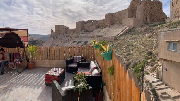 Une terrasse extérieure aménagée avec des sièges, des plantes en pot et une vue sur un fort historique.