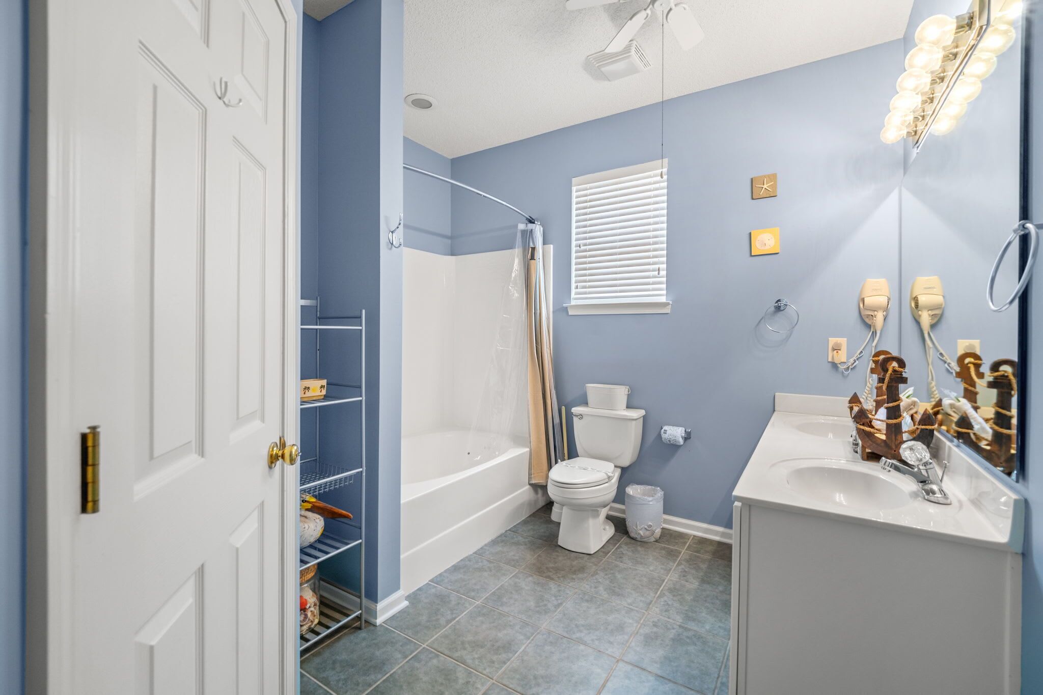 A bathroom with a bathtub, toilet, and sink, with a mirror and light fixtures.