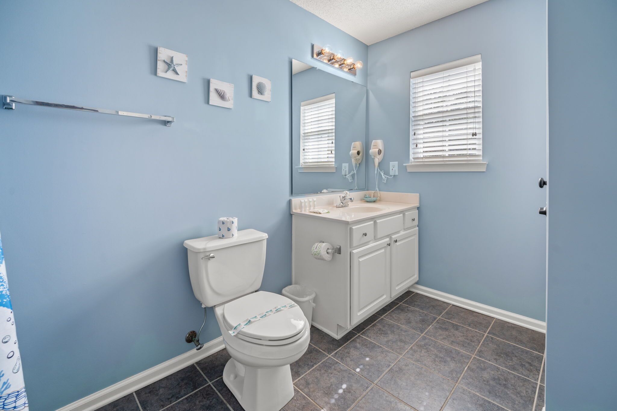 A bathroom with a toilet, sink, vanity, and a mirror.